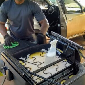 Profissional realizando higienização de banco de carro para remoção de manchas e ácaros.